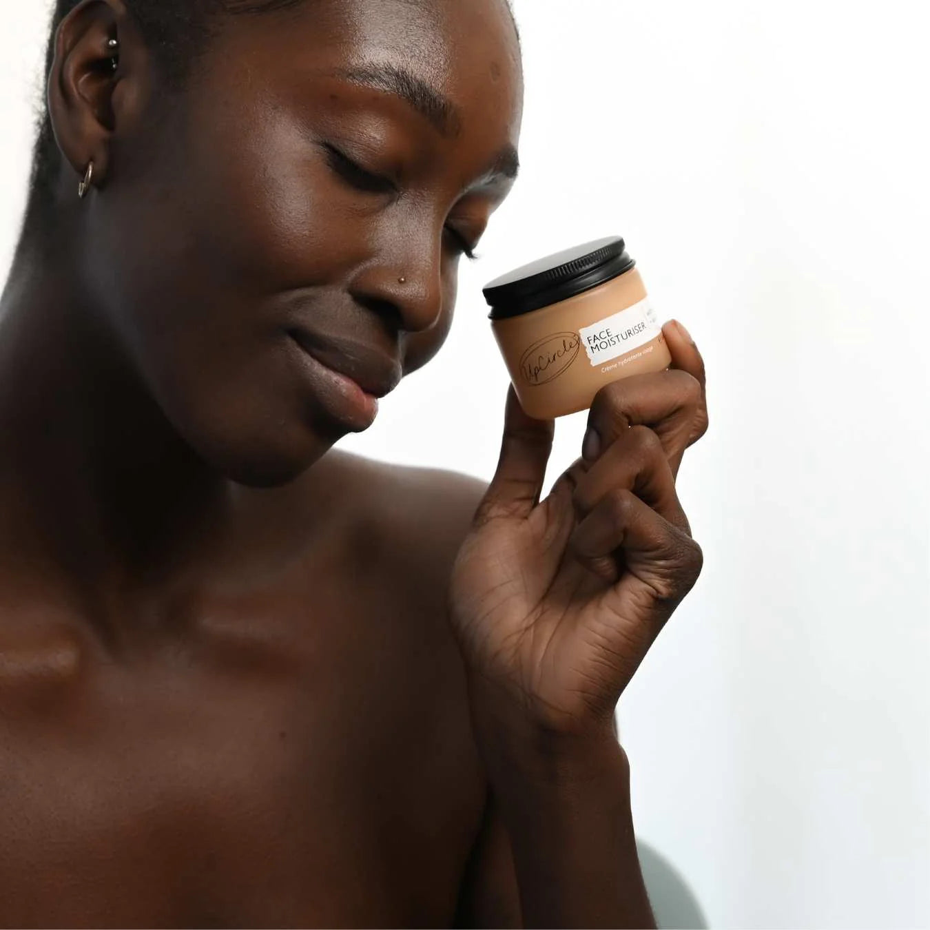 Woman holding a jar of skincare product with a neutral background