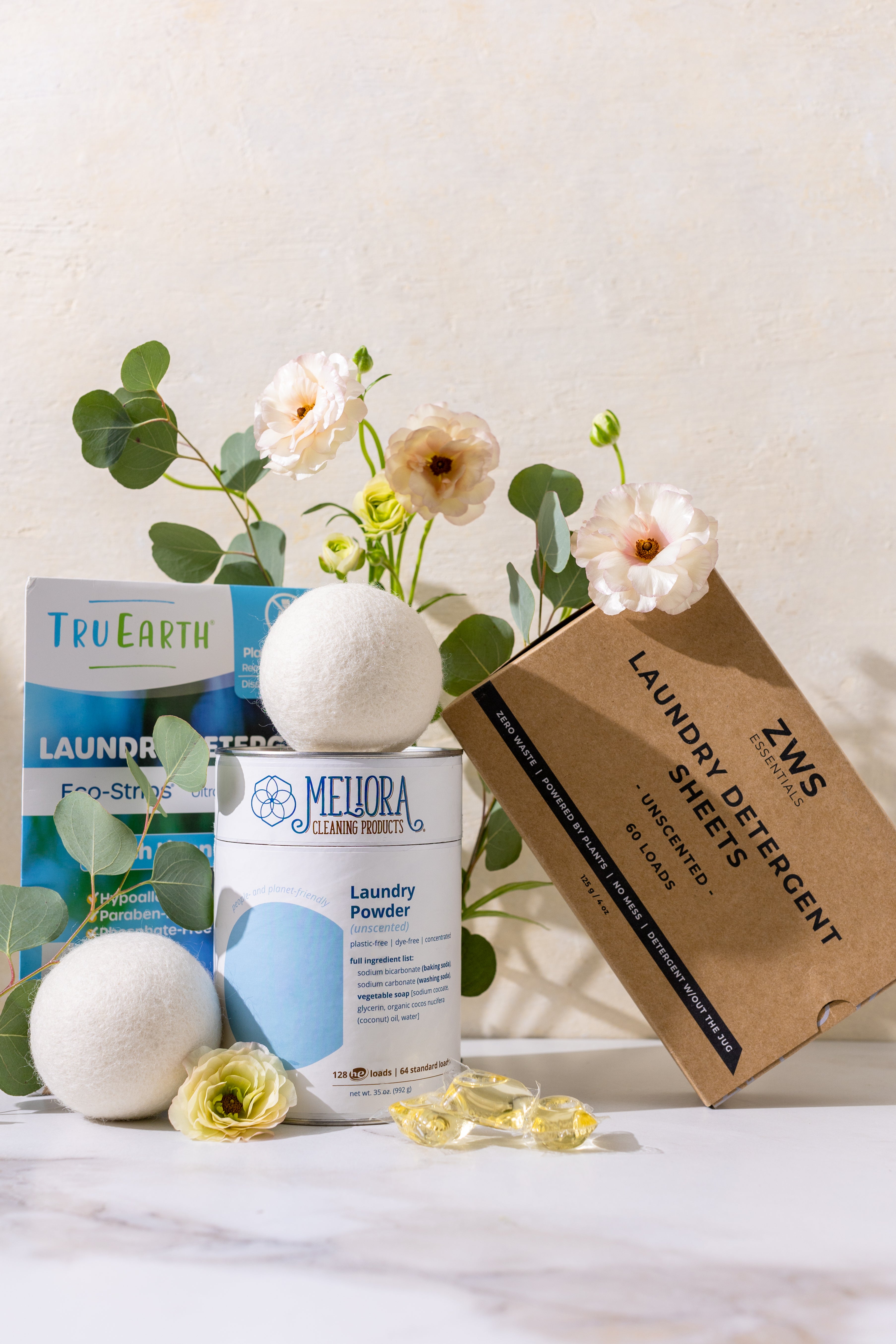 Green cleaning products and laundry items with flowers on a white background