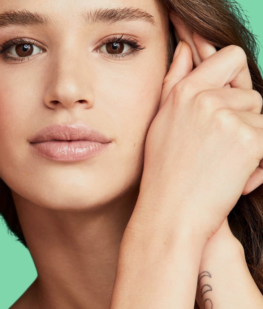 Close-up of a woman with one hand near her ear against a green background