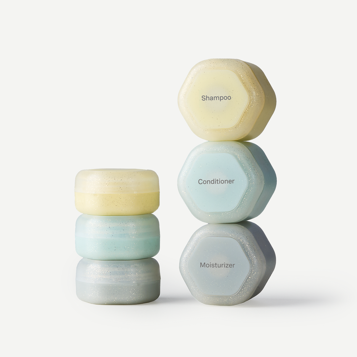 Three stacked sets of round cosmetic bars in soft pastel shades, labeled Shampoo, Conditioner, and Moisturizer on a clean white background.