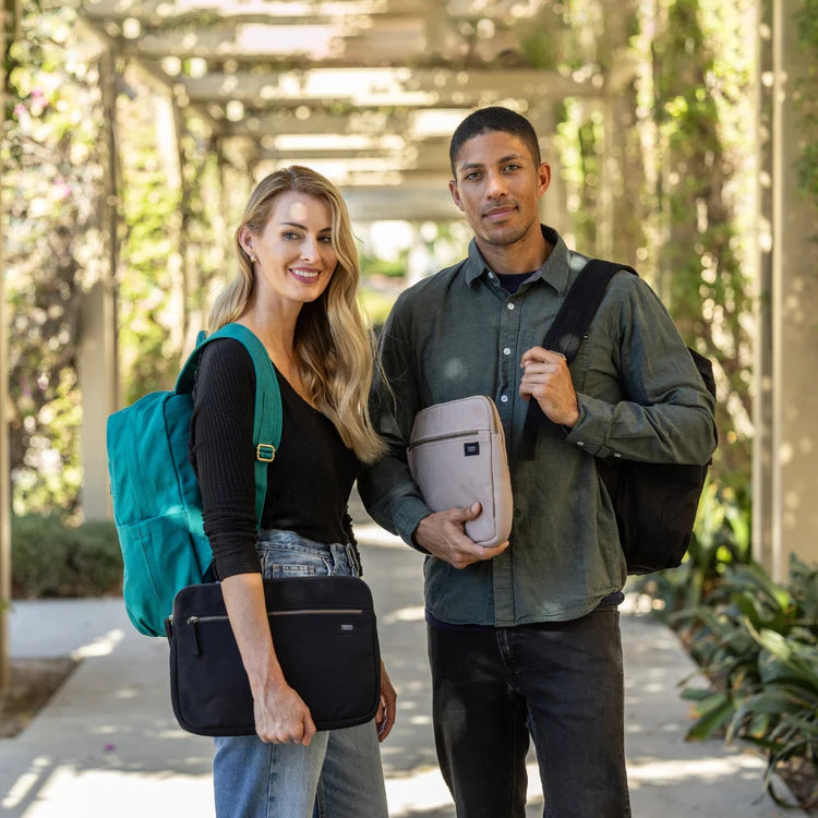 Two people standing outdoors, each holding a bag or laptop case.