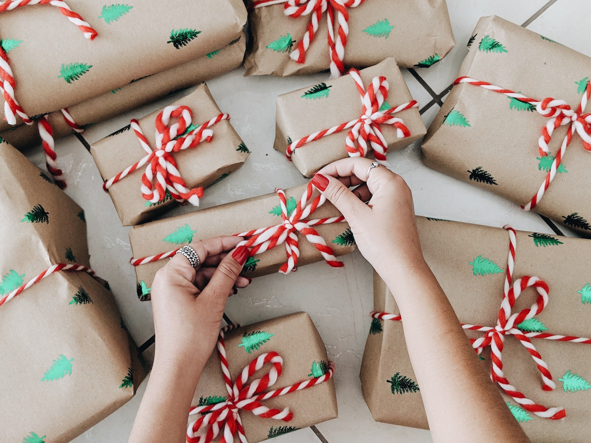  person wrapping presents with red and white ribbon. 