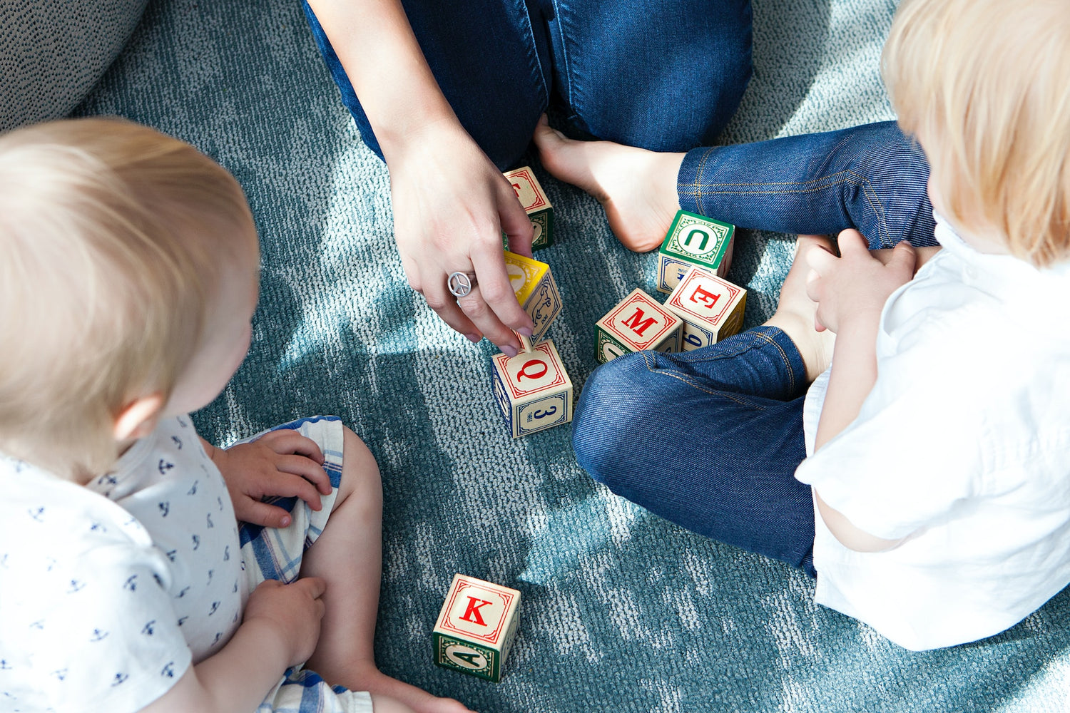 Adults and children playing with wooden alphabet blocks