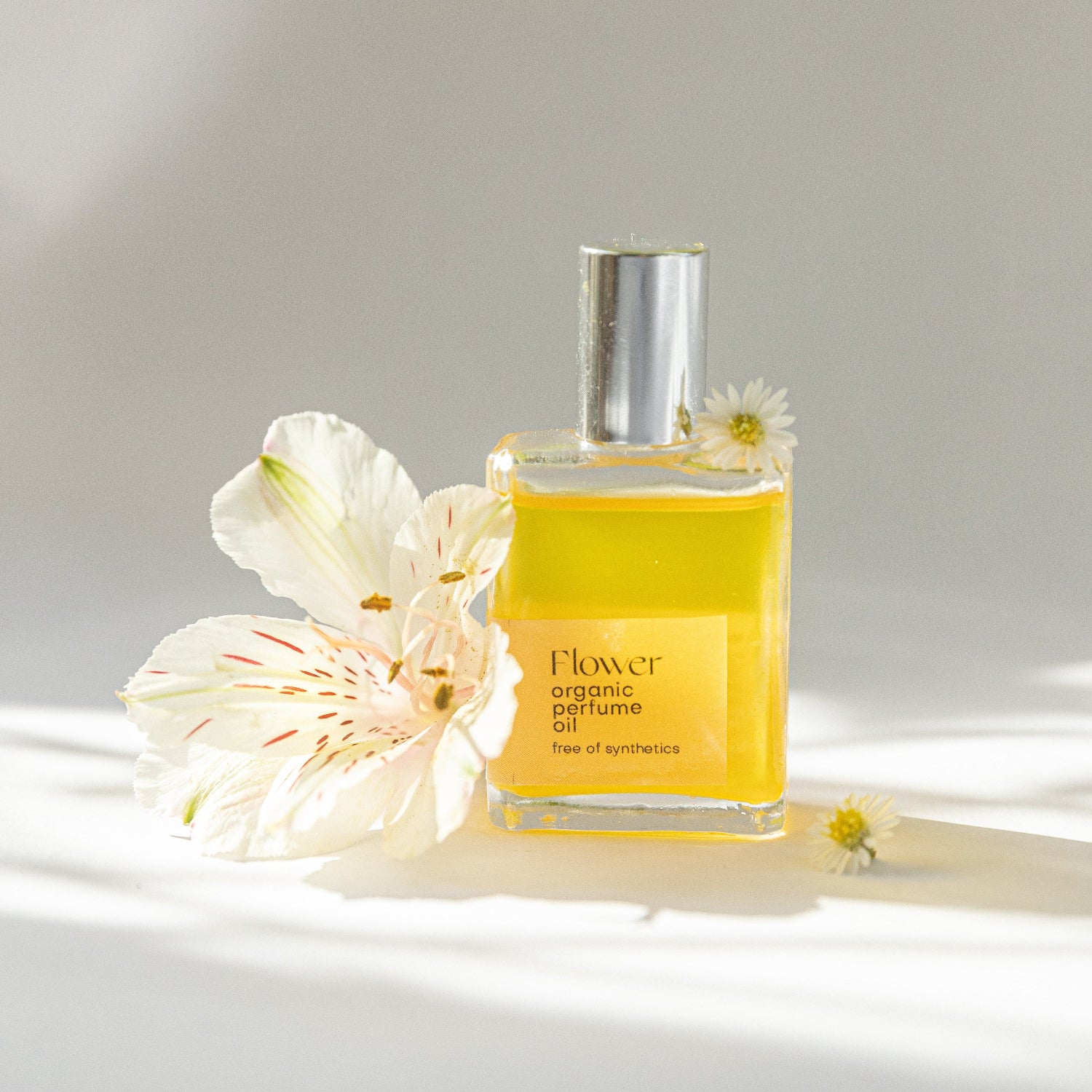 Yellow perfume bottle with flowers on a light background
