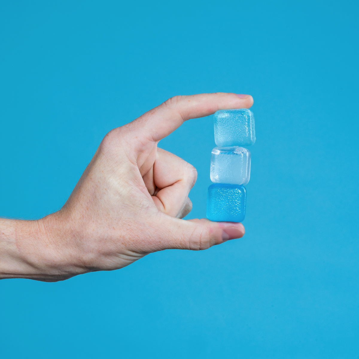 Hand holding two small blue containers against a blue background