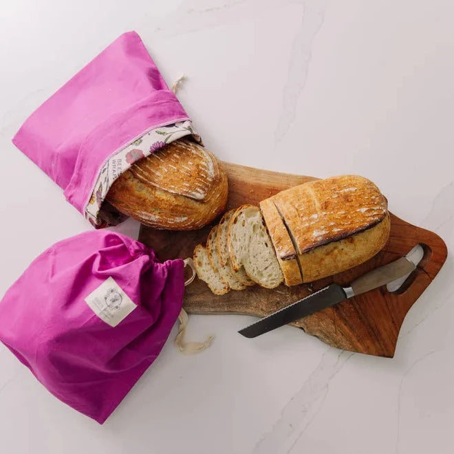 Loaf of bread on cutting board and bread in bee's wrap bread bag 
