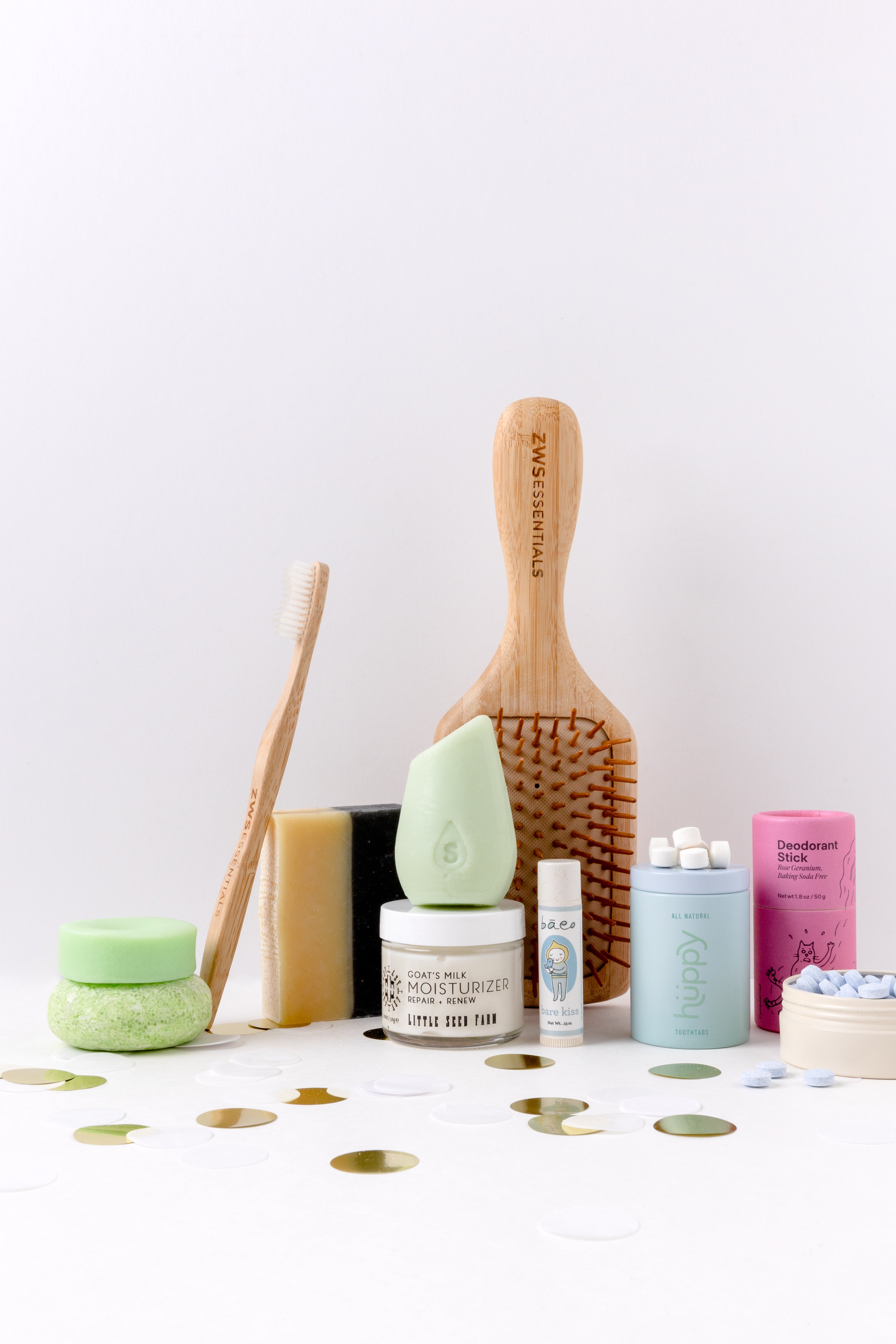 Collection of natural beauty products including a hairbrush, soap, and skincare items on a white background.