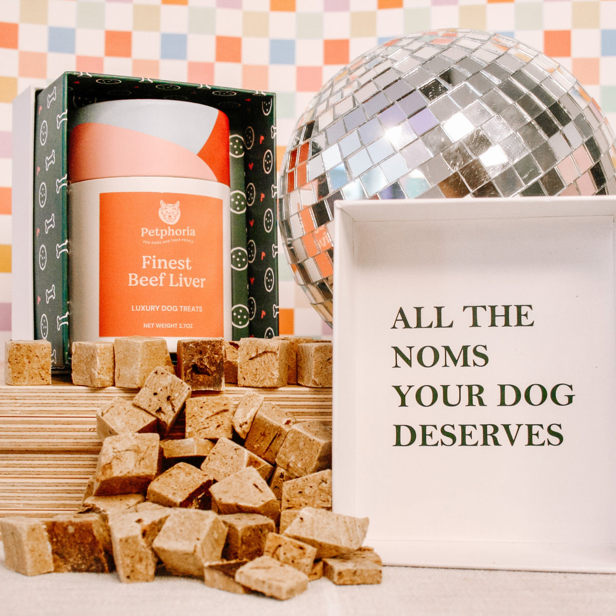 Dog treats, a disco ball, and a sign with text on a colorful checkered background