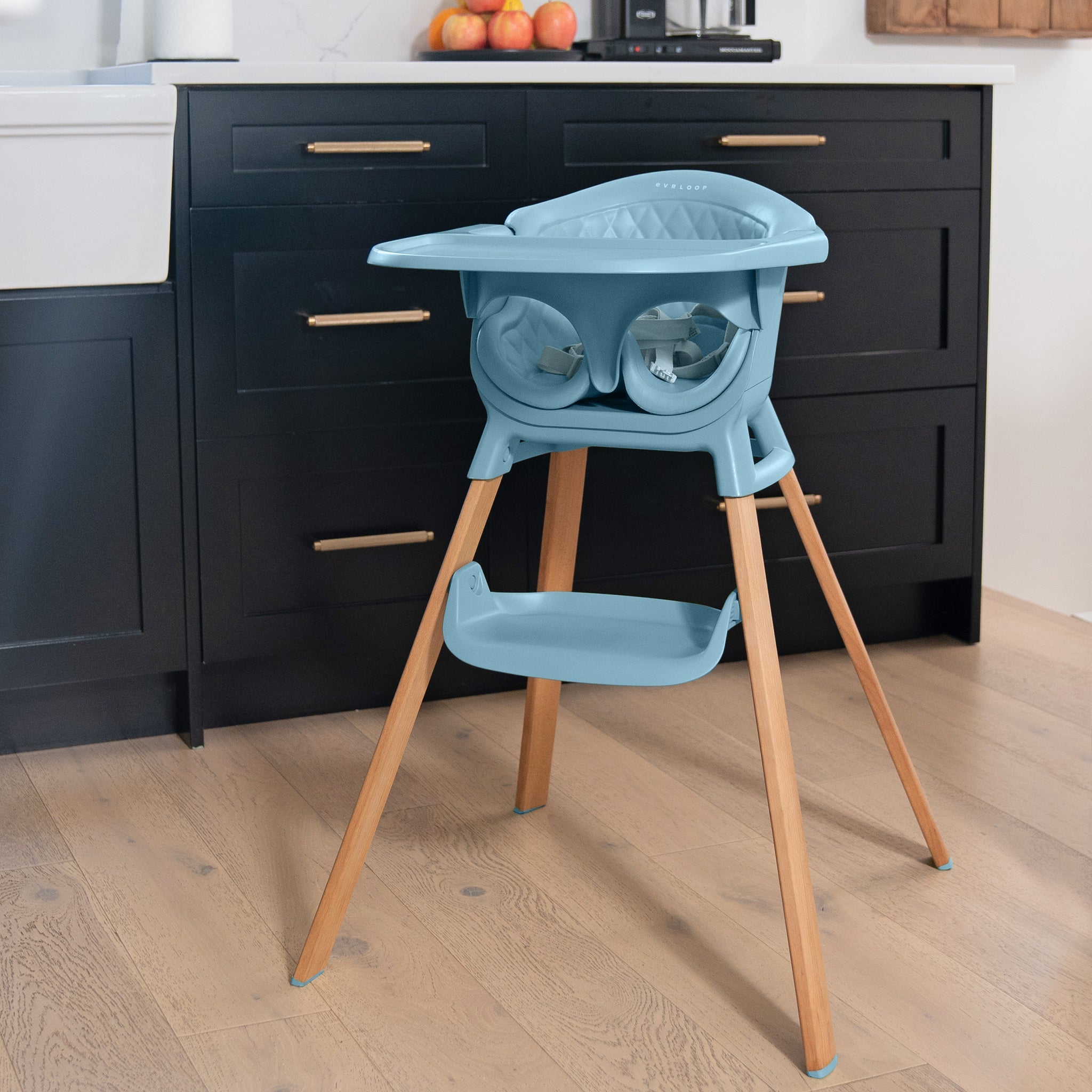 Blue baby high chair with wooden legs in a kitchen setting