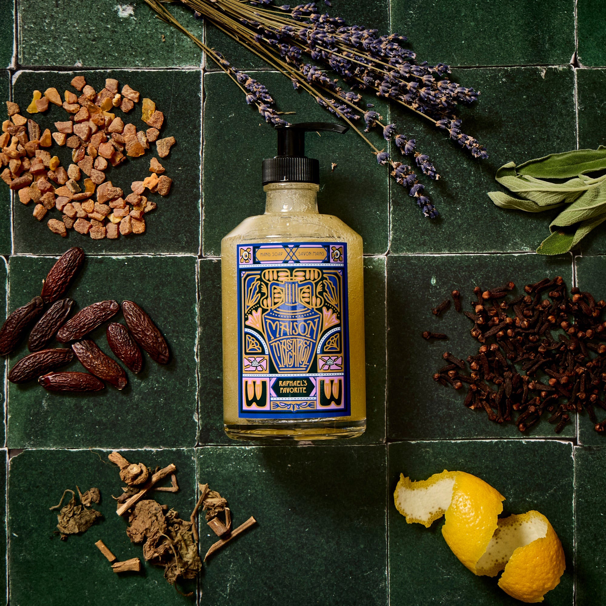 Bottle of soap with decorative label surrounded by dried herbs and lavender on a green tiled background