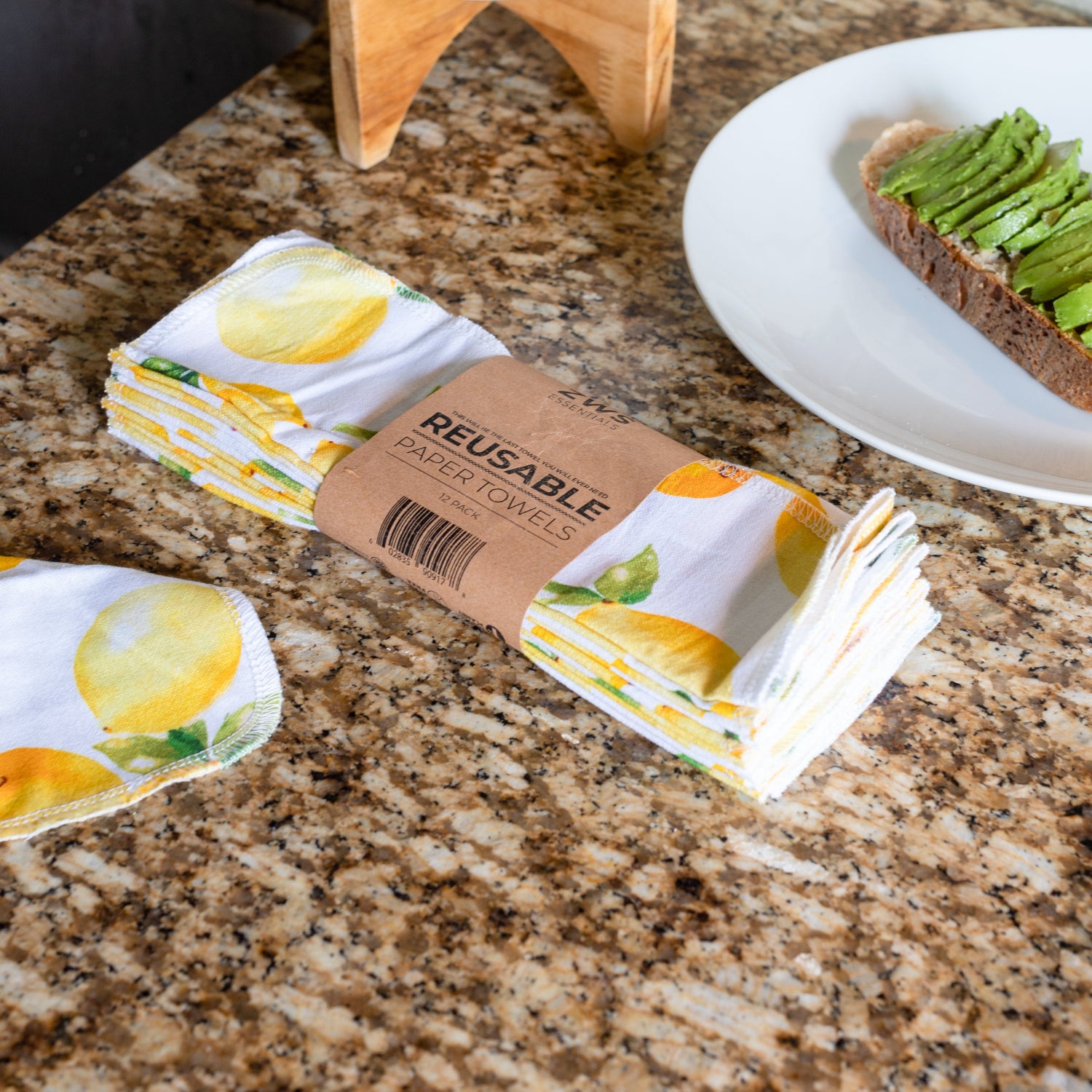 Reusable paper towels with lemon design on a granite countertop next to a plate of avocado toast.