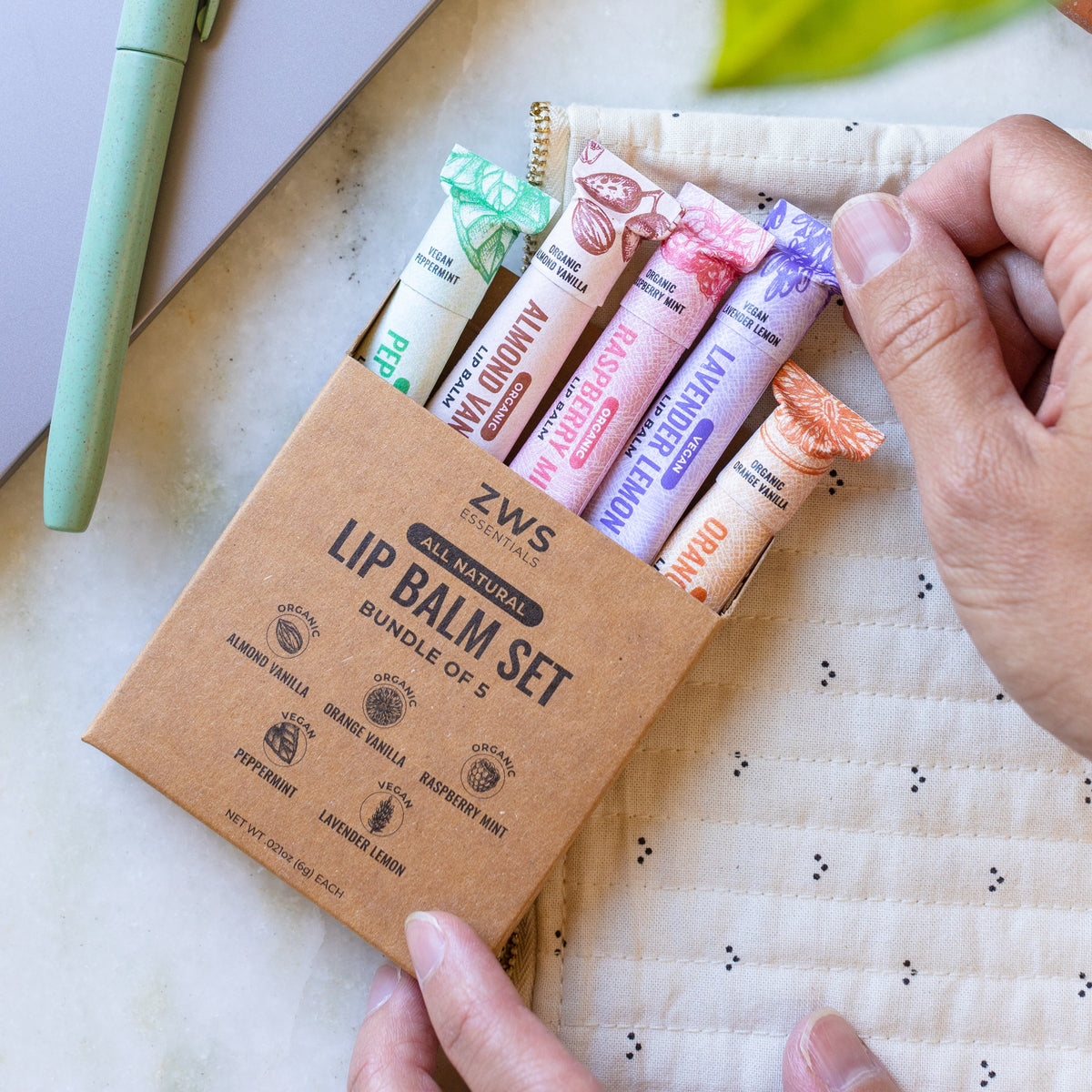 hands holding the ZWS Essentials All Natural Lip Balm Set Bundle of 5, almond vanilla, orange vanilla, Raspberry Mint, Peppermint, Lavender Lemon kit
