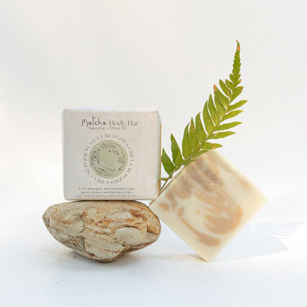 Bar of soap, packaging, and a leaf on a white background