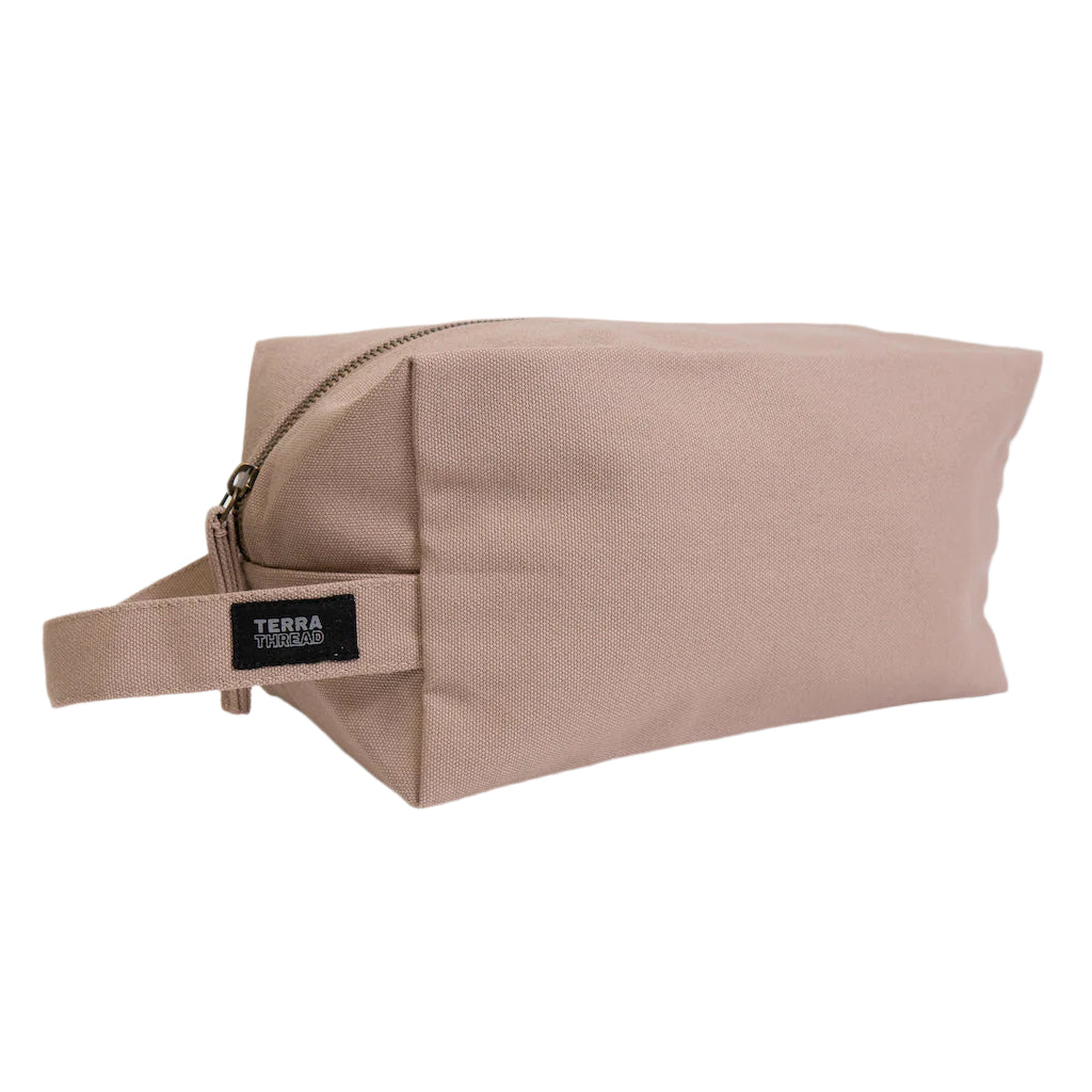Beige toiletry bag with a strap on a light gray background