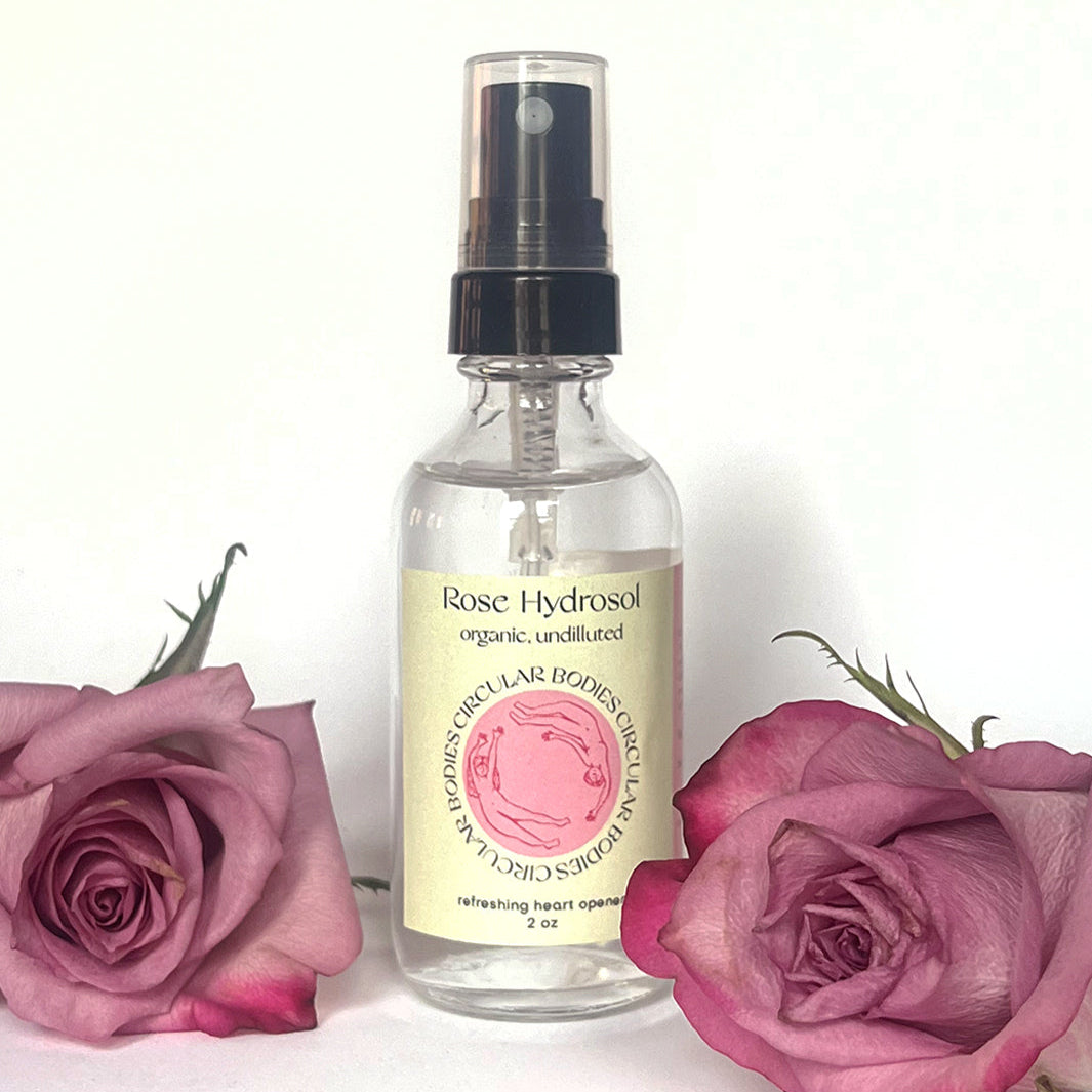 Rose hydrosol spray bottle with pink roses on a white background
