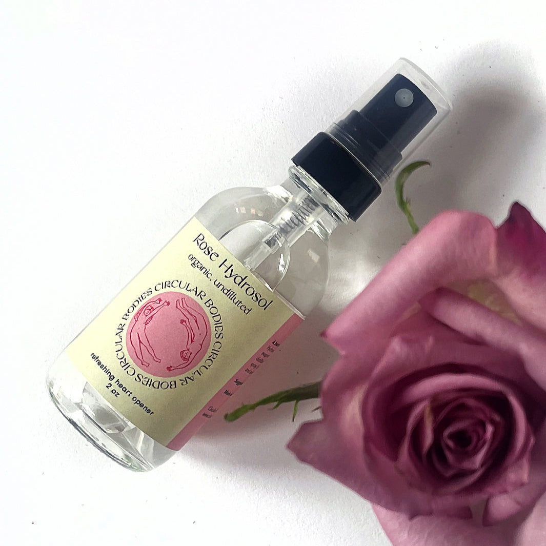 Bottle of rose hydrosol with a pink rose on a white background